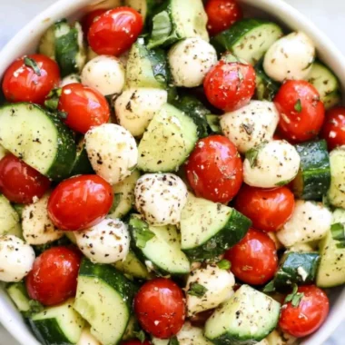 Cucumber Caprese salad with tomatoes, mozzarella, and fresh basil on a white plate