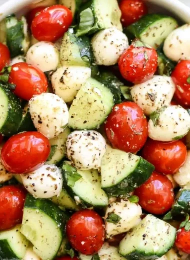 Cucumber Caprese salad with tomatoes, mozzarella, and fresh basil on a white plate