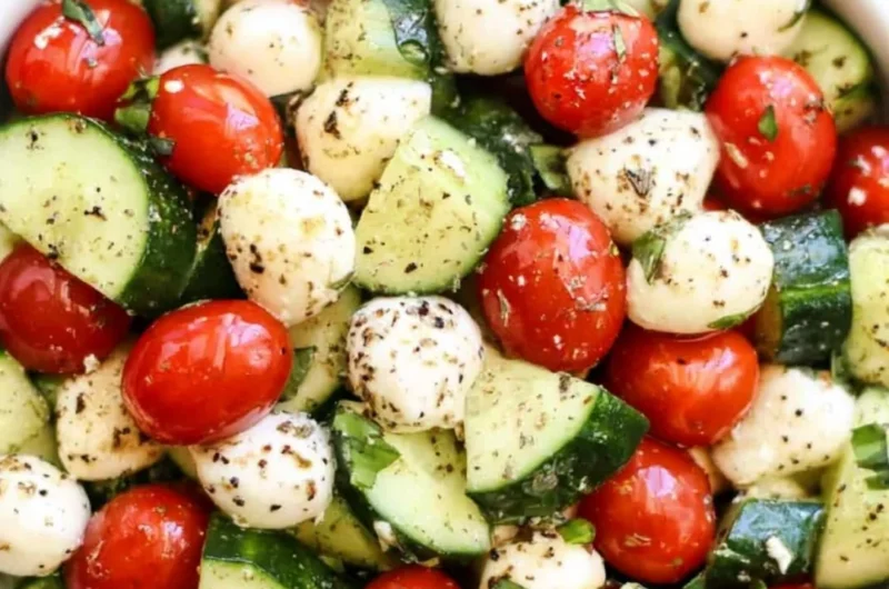 Cucumber Caprese salad with tomatoes, mozzarella, and fresh basil on a white plate