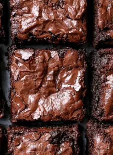 Fudgiest brownies topped with chocolate icing on a wooden table