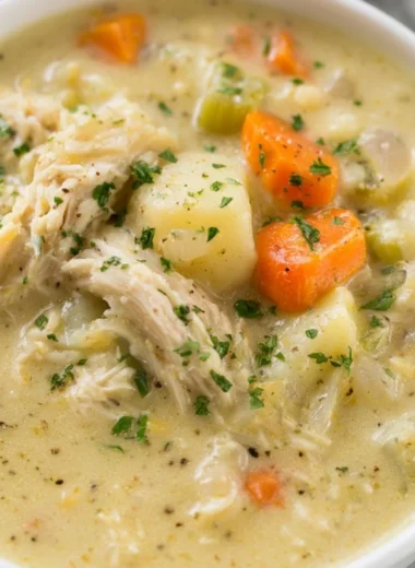 A bowl of healthy chicken pot pie soup with vegetables and herbs
