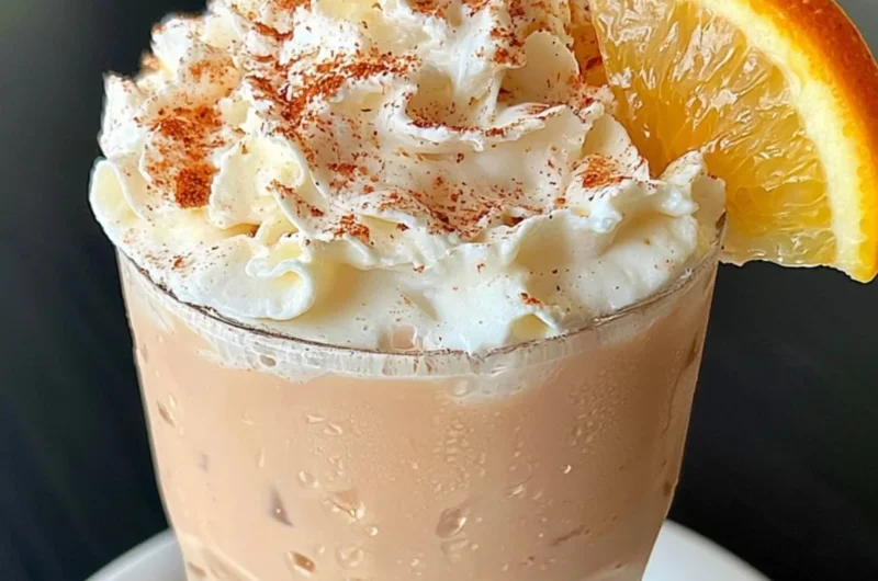 A cup of orange cinnamon milk tea with vibrant colors and spices.